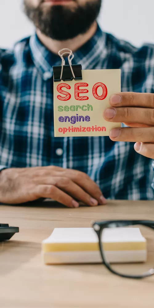 cropped shot of young bearded developer holding sticker with SEO - search engine optimization
